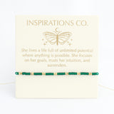 Bracelet with green beads on a card from Inspirations Co. featuring a butterfly design.