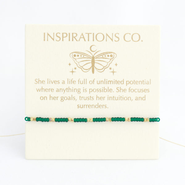 Bracelet with green beads on a card from Inspirations Co. featuring a butterfly design.