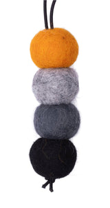 Four felted balls in black, gray, white, and yellow on a white background