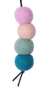 Set of four felted wool balls in blue, green, beige, and pink on a white background