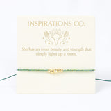 Bracelet with gold beads on a card from Inspirations Co. with a quote.
