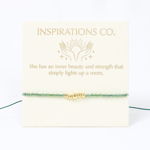 Bracelet with gold beads on a card from Inspirations Co. with a quote.