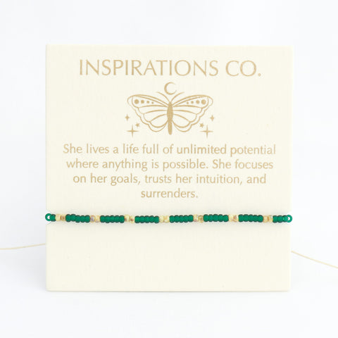 Bracelet with green beads on a card from Inspirations Co. featuring a butterfly design.