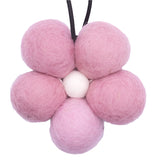 Pink felt balls arranged in a flower shape on a white background