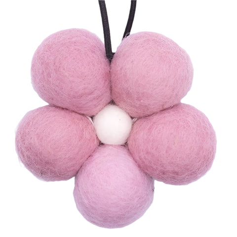 Pink felt balls arranged in a flower shape on a white background