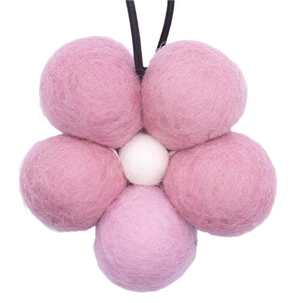 Pink felt balls arranged in a flower shape on a white background