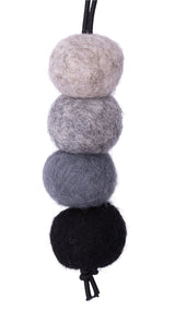 Four felted wool balls in black, gray, and beige on a white background