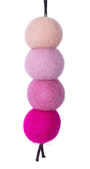 Set of four pink and beige felted wool balls on a white background