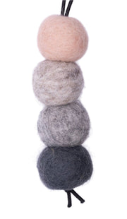 Set of four felted wool balls in gray, beige, and black on a white background