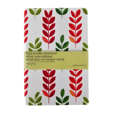 Notebook with red and green leaf pattern and motivational quote on a white background