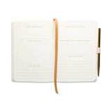 White journal with a brown strap and pen on a white background
