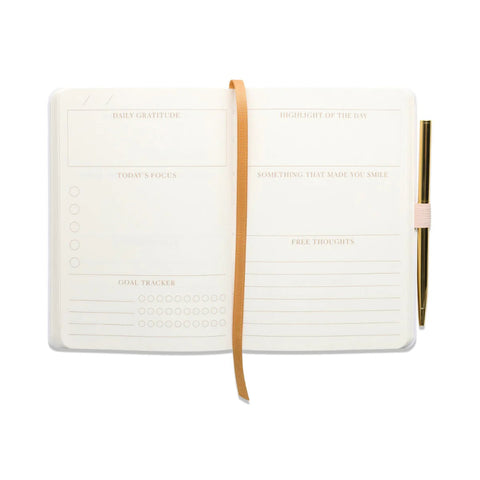 White journal with a brown strap and pen on a white background