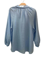 Light blue blouse on a hanger against a plain background