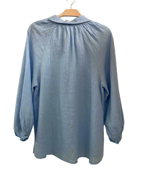 Light blue blouse on a hanger against a plain background