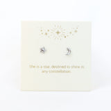 Silver star and moon earrings on a decorative card with gold text and designs.