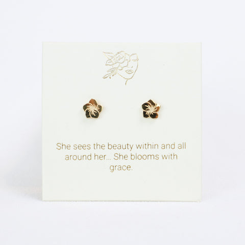 Gold floral earrings on a card with motivational quote on a white background
