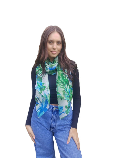 Woman wearing a colorful scarf standing in front of green foliage