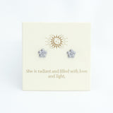 Flower-shaped earrings on a card with motivational text and logo.