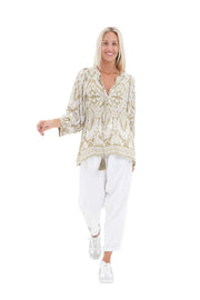 Woman wearing a patterned blouse and white pants on a white background